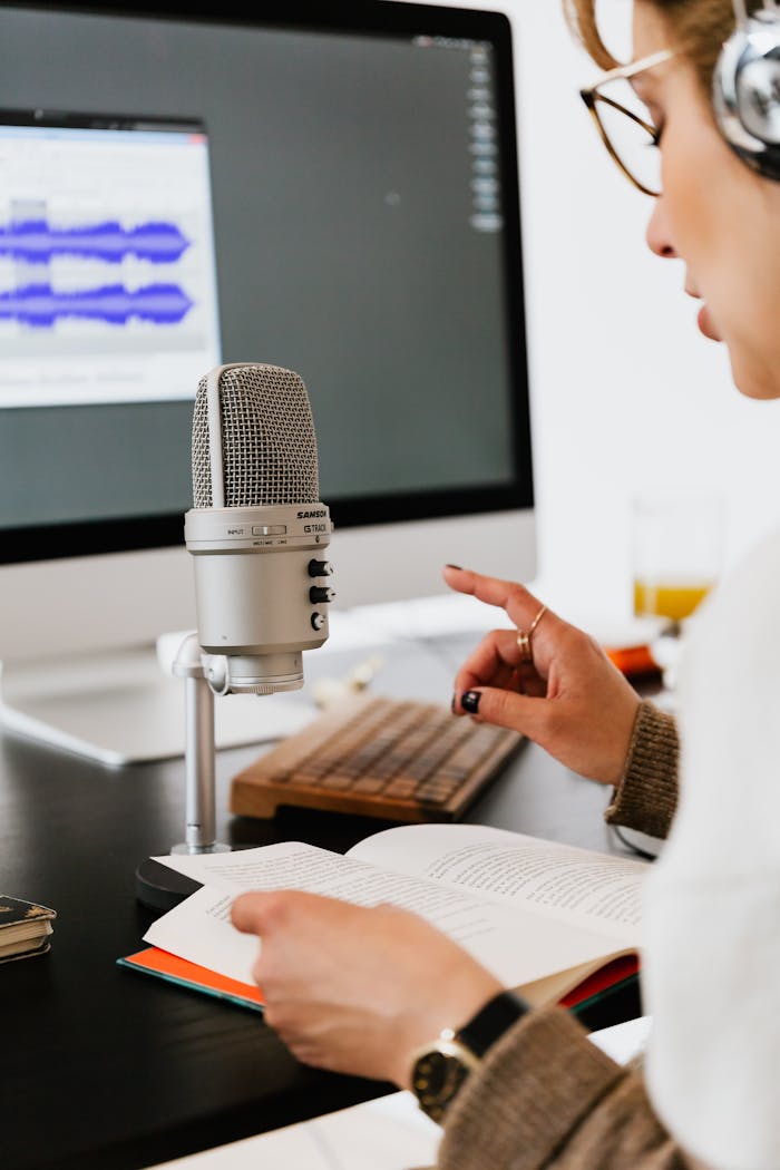 gallery-4 A person recording an audiobook using a professional microphone and headphones indoors.