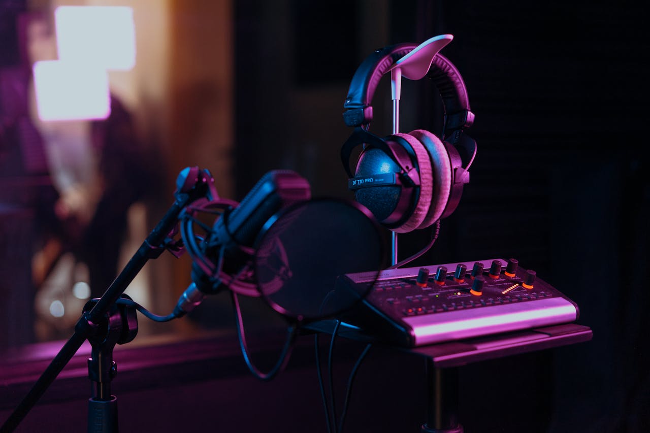 gallery-3 High-quality audio recording studio setup with a microphone, headphones, and mixer board in dim lighting.