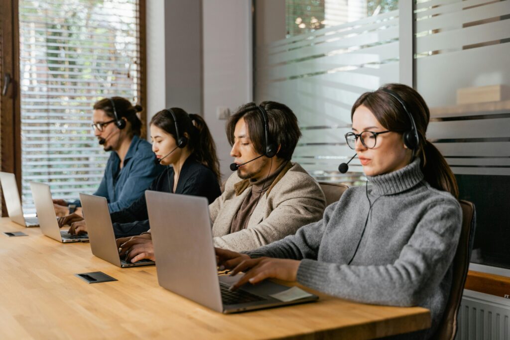pexels photo 7709189 7709189 A diverse call center team uses laptops and headsets to provide customer support efficiently.